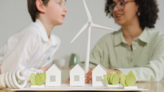 A woman and young boy chat behind a display of houses and a wind turbine